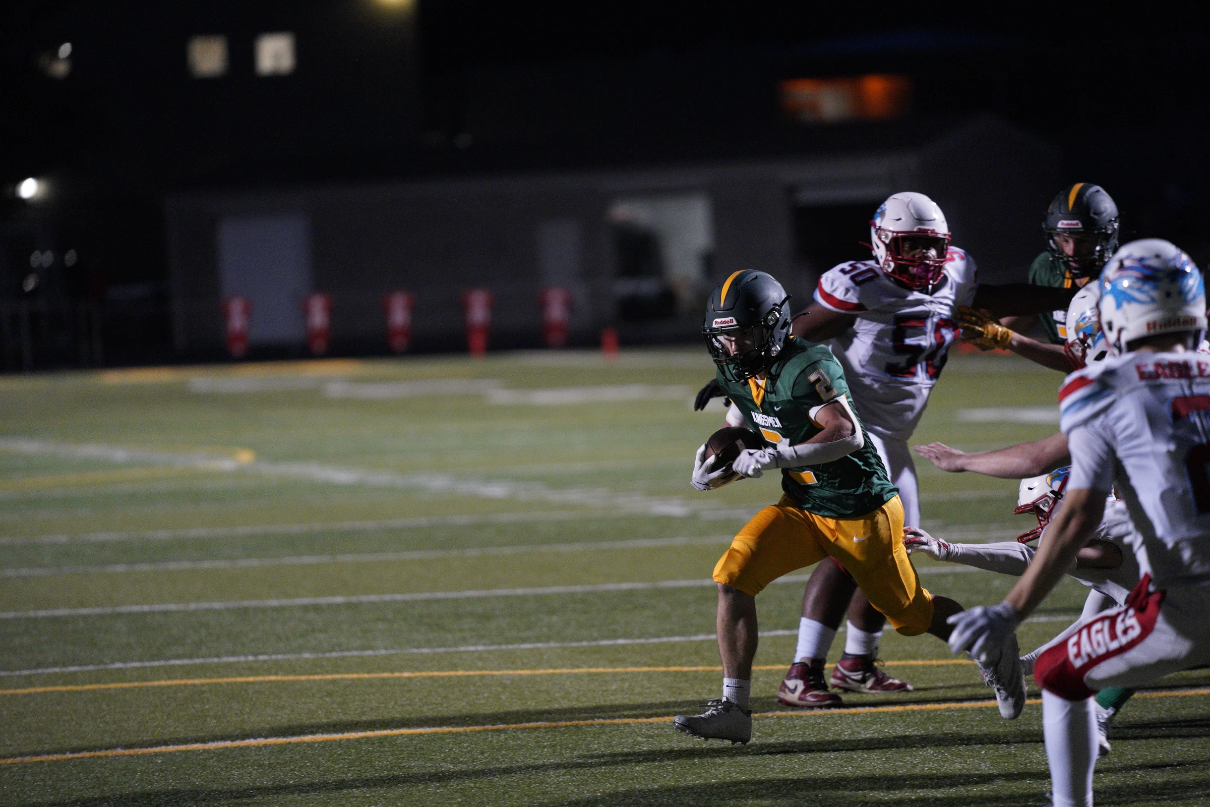 Rex Putnam football player carrying the ball under stadium lights